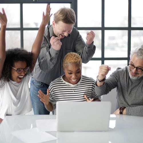Canva - Excited multiracial colleagues enjoying triumph together in front of laptop in office Canva - Excited multiracial colleagues enjoying triumph together in front of laptop in office